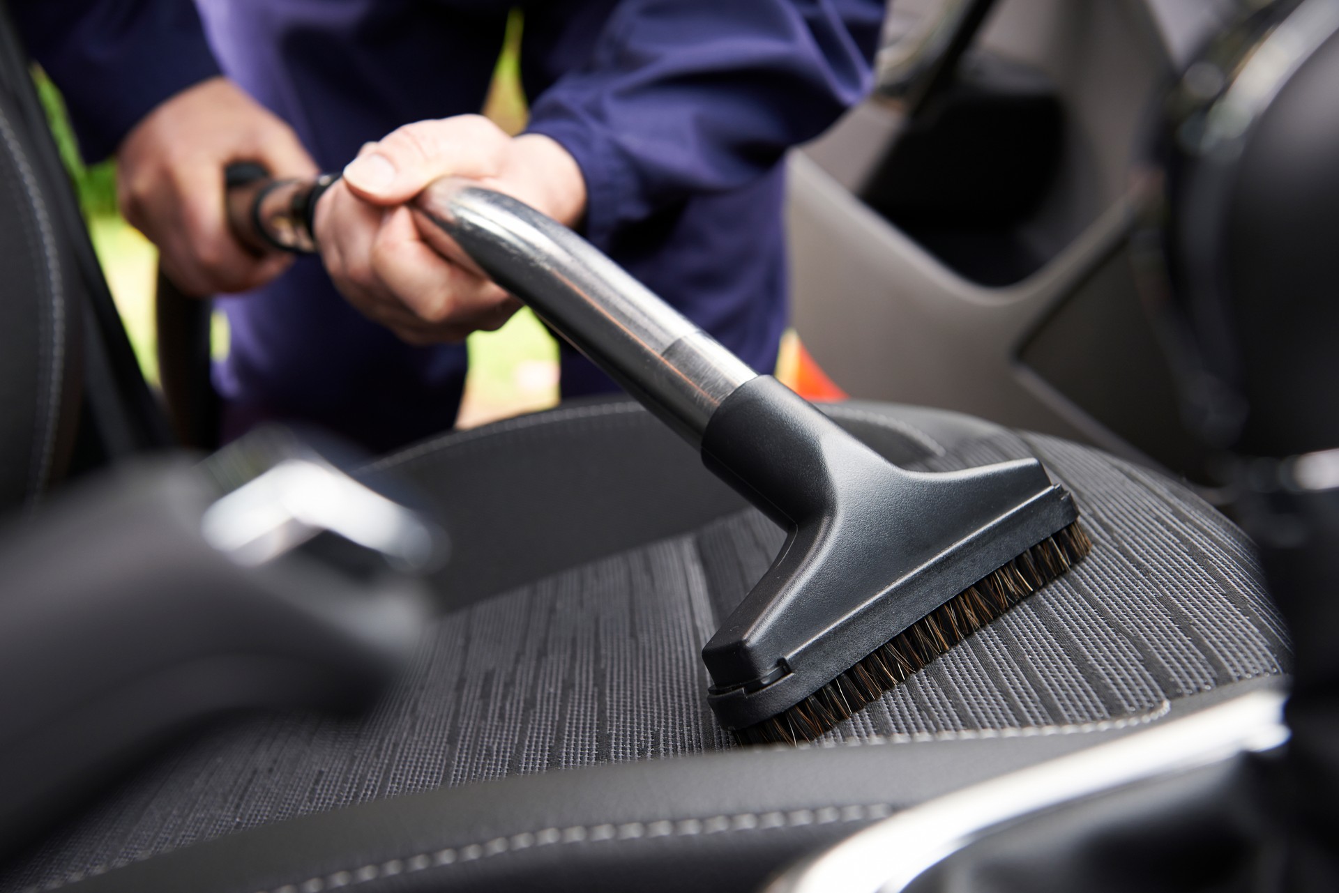 Man Hoovering Seat Of Car During Car Cleaning