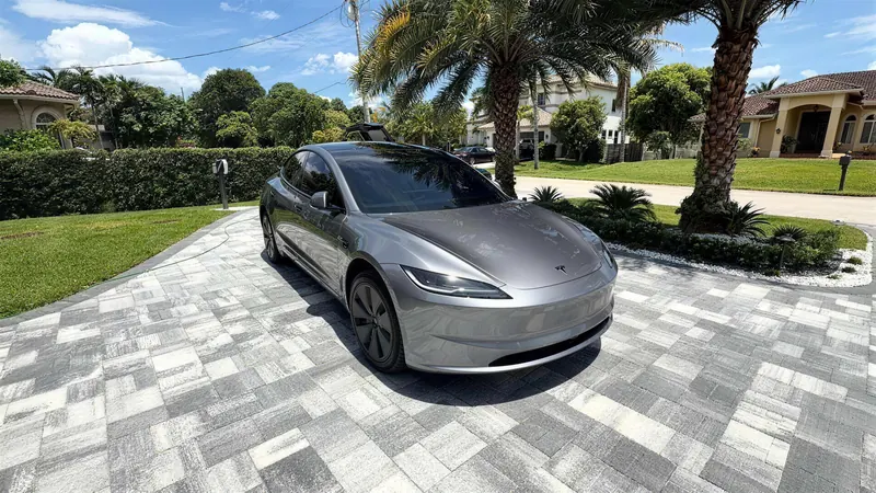 Tesla plateado recién detallado en una entrada con palmeras